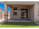 Covered back patio with artificial turf, stucco columns, and sliding glass doors at 18374 W Poston Dr, Surprise, AZ 85387