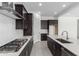 Modern kitchen featuring dark wood cabinets, a stainless steel hood, and a center island with a built-in sink and dishwasher at 21845 E Bonanza Ct, Queen Creek, AZ 85142