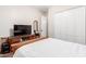 Bright bedroom with a wooden bed frame, a TV on a wooden stand and white closets at 22847 N 53Rd E St, Phoenix, AZ 85054