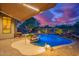 Backyard view of an illuminated pool with patio and desert landscaping under an awning at dusk at 22847 N 53Rd E St, Phoenix, AZ 85054