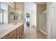 Well-lit bathroom features double sinks, a large mirror, shower, and tile flooring at 25659 W Forest Grove Ave, Buckeye, AZ 85326