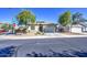 Attractive single story home features a xeriscaped front yard with healthy trees under a blue sky at 25659 W Forest Grove Ave, Buckeye, AZ 85326