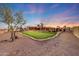 Expansive backyard with putting green, desert landscaping, and an architectural home in the background at 28758 N Ashbrook Ln, San Tan Valley, AZ 85144