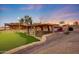 Backyard with custom stone feature, putting green, desert landscaping, and a beautiful sunset backdrop at 28758 N Ashbrook Ln, San Tan Valley, AZ 85144