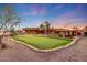 Spacious backyard featuring a putting green, desert-style landscaping, and a stylish home at dusk at 28758 N Ashbrook Ln, San Tan Valley, AZ 85144