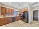 Kitchen featuring travertine tile, wood cabinets, black appliances and tile backsplash at 28758 N Ashbrook Ln, San Tan Valley, AZ 85144