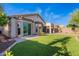 Lush backyard with artificial grass, a covered patio, and mature desert trees at 3055 N Red Mtn # 122, Mesa, AZ 85207