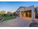 Backyard with a covered patio, artificial grass, and mature desert landscaping at dusk at 3055 N Red Mtn # 122, Mesa, AZ 85207