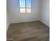 A sunlit bedroom with wood-look tile flooring and a bright window at 3637 E Rochelle Cir, Mesa, AZ 85213