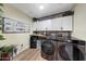 Well-organized laundry room with white cabinets, modern washer and dryer, and stylish decor at 41143 W Rio Bravo Dr, Maricopa, AZ 85138