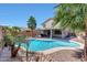 Backyard oasis featuring a sparkling pool, patio area, and tropical landscaping with palm trees at 41143 W Rio Bravo Dr, Maricopa, AZ 85138