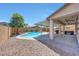 A backyard area featuring a refreshing pool, covered patio with a fan, and desert landscaping at 41143 W Rio Bravo Dr, Maricopa, AZ 85138