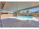 A covered patio overlooks a private pool, surrounded by lush palm trees and desert landscaping at 41143 W Rio Bravo Dr, Maricopa, AZ 85138