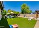 Spacious backyard with artificial turf, swimming pool, lounge chairs, dining area, and pergola at 4932 E Kathleen Rd, Scottsdale, AZ 85254