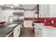 Modern kitchen featuring white cabinets, stainless steel appliances, red backsplash, and a spacious sink area at 6746 E Monterosa St, Scottsdale, AZ 85251
