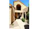 Exterior arched entry with black metal trimmed door, neutral exterior, and desert landscaping at 9115 N 101St Way, Scottsdale, AZ 85258