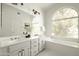 A bright bathroom features a tub, double sink vanity, and a large window at 9224 E Windrose Dr, Scottsdale, AZ 85260