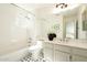 Bright bathroom featuring a tub/shower combo, patterned tile floor, and a large mirror at 9224 E Windrose Dr, Scottsdale, AZ 85260