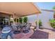 Inviting covered patio with seating area, surrounded by lush landscaping and vibrant bougainvillea at 10526 W Tonopah Dr, Peoria, AZ 85382
