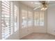 Bright sitting area with multiple windows dressed with white shutters and a ceiling fan at 10526 W Tonopah Dr, Peoria, AZ 85382