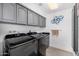 Functional laundry room with gray cabinets, a sink, modern washer and dryer, and tile floors at 10662 E Carol Ave, Scottsdale, AZ 85258