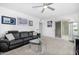 Comfortable living room boasts a black leather sofa, glass table, ceiling fan, and artwork on the white walls at 10662 E Carol Ave, Scottsdale, AZ 85258