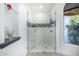 Modern shower featuring a glass enclosure, tiled walls with decorative accents, and a built-in bench for added comfort at 10662 E Carol Ave, Scottsdale, AZ 85258