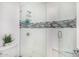 Large shower features white tile, gray accent tile, a glass door, built-in seat, and toiletry storage at 10662 E Carol Ave, Scottsdale, AZ 85258