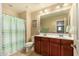 Bright bathroom with dual sinks, modern fixtures, tile flooring, and a decorative shower curtain at 10718 E Vivid Ave, Mesa, AZ 85212
