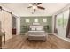 Serene bedroom featuring wood-look floors, a sliding barn door, and three windows offering natural light and a view at 10718 E Vivid Ave, Mesa, AZ 85212