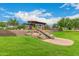 Community playground featuring a slide, lush green grass, and a shaded seating area for families at 10718 E Vivid Ave, Mesa, AZ 85212