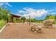 Community playground with climbing rocks, swings, wood chip ground cover, and a shaded picnic area at 10718 E Vivid Ave, Mesa, AZ 85212