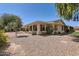 Exterior elevation of the desert landscaped home featuring mature trees and a covered patio at 12927 W Shadow Hills Dr, Sun City West, AZ 85375