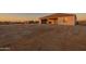 Home's backyard patio awaiting landscaping, set against a desert backdrop at dusk at 13430 S Garnet Rd, Buckeye, AZ 85326