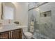 Bathroom with a marble-tiled walk-in shower, stone sink, wooden cabinets, and brushed nickel hardware at 13430 S Garnet Rd, Buckeye, AZ 85326
