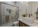 Bathroom with a stone sink, wooden cabinets, and a marble-tiled walk-in shower at 13430 S Garnet Rd, Buckeye, AZ 85326