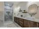 Bathroom featuring double sink vanity, framed mirrors, sconces, and a glass-enclosed shower at 13430 S Garnet Rd, Buckeye, AZ 85326