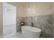 Bathroom showcasing a soaking tub, tiled accent wall and floor, and view to living area at 13430 S Garnet Rd, Buckeye, AZ 85326
