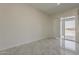 Open-concept living room featuring neutral walls, tile flooring, and a glass sliding door at 13430 S Garnet Rd, Buckeye, AZ 85326