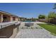 A spacious backyard featuring a pool, fire pit, and outdoor kitchen area at 15655 W Berkeley Rd, Goodyear, AZ 85395