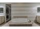 Inviting bathroom with a tiled soaking tub, walk-in closet, and and vanities with soft blue walls at 15655 W Berkeley Rd, Goodyear, AZ 85395
