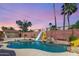 Backyard pool with a slide and a small cabana surrounded by desert landscaping and a brick wall at 15825 N 45Th St, Phoenix, AZ 85032