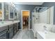 Bathroom with double sinks, glass enclosed shower, soaker tub, and an open walk-in closet at 18633 W Mcneil St, Goodyear, AZ 85338
