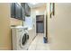 Efficient laundry room with tile floor, black cabinets, modern washer and dryer, and neutral wall color at 18633 W Mcneil St, Goodyear, AZ 85338