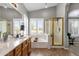 Bathroom featuring double sinks, large mirror, soaking tub, glass-enclosed shower, and a large window at 20239 N 39Th Dr, Glendale, AZ 85308
