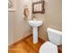 Well-lit bathroom features a pedestal sink, decorative mirror, and hardwood flooring at 2103 E Canyon Pl, Chandler, AZ 85249