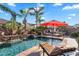 Stunning backyard swimming pool with rock waterfall, lush landscaping, lounge chairs, and a red umbrella, perfect for outdoor relaxation at 2103 E Canyon Pl, Chandler, AZ 85249
