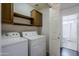 Laundry room with white washer and dryer, shelving, and doorway to bathroom with tile shower at 2135 S Bristol --, Mesa, AZ 85209