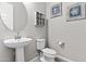 Well-lit bathroom with a pedestal sink and a toilet, decorated with nautical themed wall art and neutral walls at 23097 N 95Th Dr, Peoria, AZ 85383
