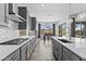 Modern kitchen with grey cabinetry, stainless steel appliances, a spacious island, and an open layout to dining area at 23097 N 95Th Dr, Peoria, AZ 85383
